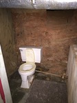 "Half Bath" per Property Description. (Dirt Wall Behind Toilet with Crawl Space Access Opening at Top Right of Photo)